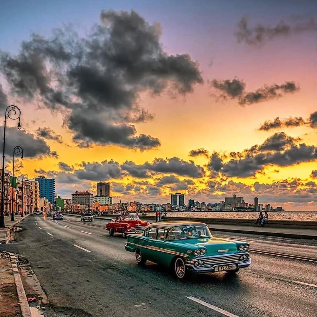 Classic car driving along the Malecón at sunset